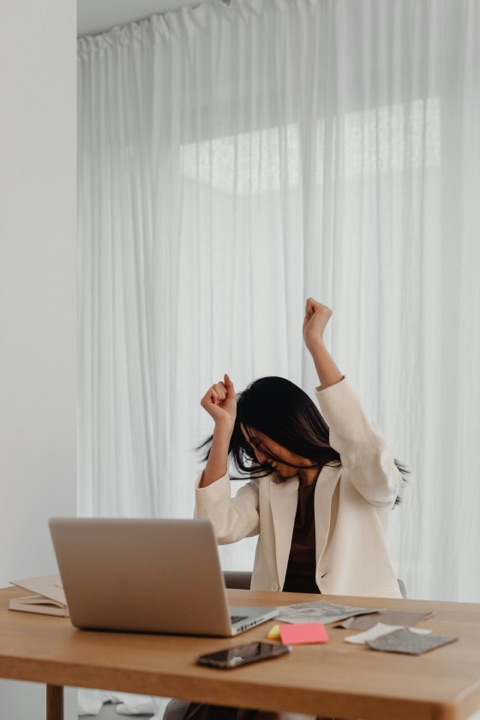 Professional celebrating at her desk with both fists raised