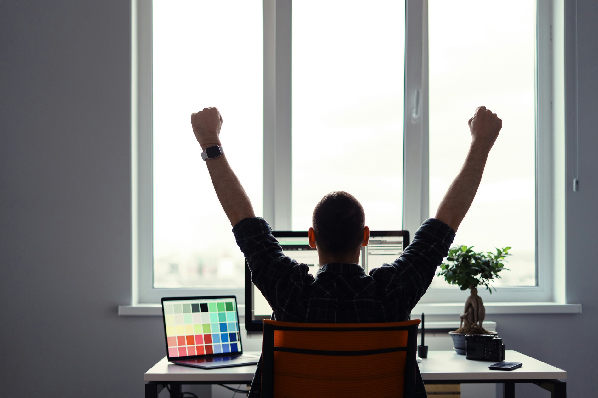 Person raising both fists in celebration at a desk