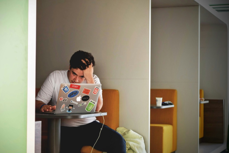 Professional at a laptop in an office booth, head in hand