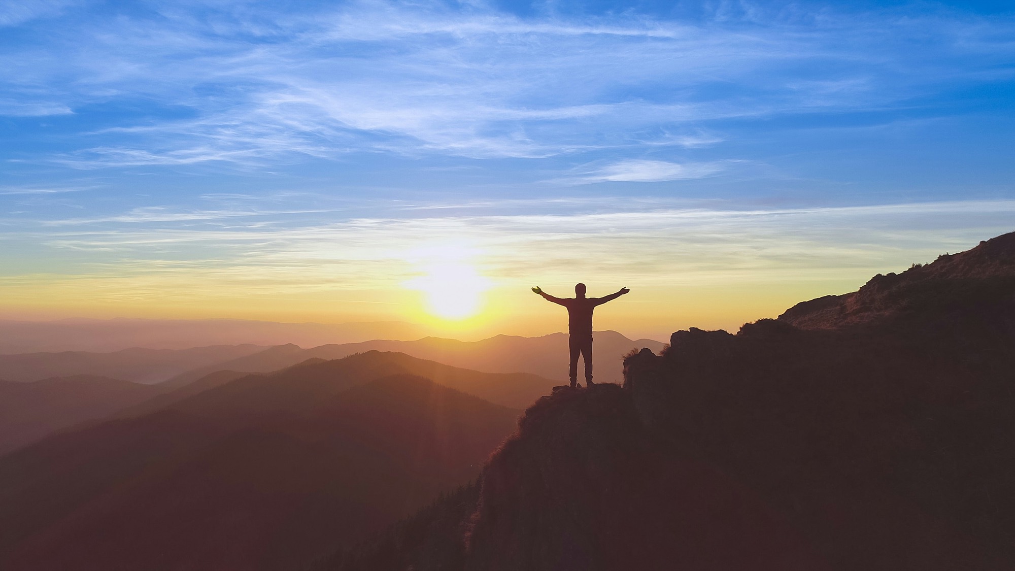 Hiker silhouetted on a summit at sunrise